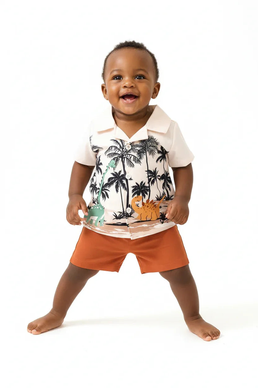 Angle bas bébé garçon en ensemble dinosaures palmiers BabyCoton — short terracotta et chemise polo beige imprimée dinos tropicaux, fond blanc