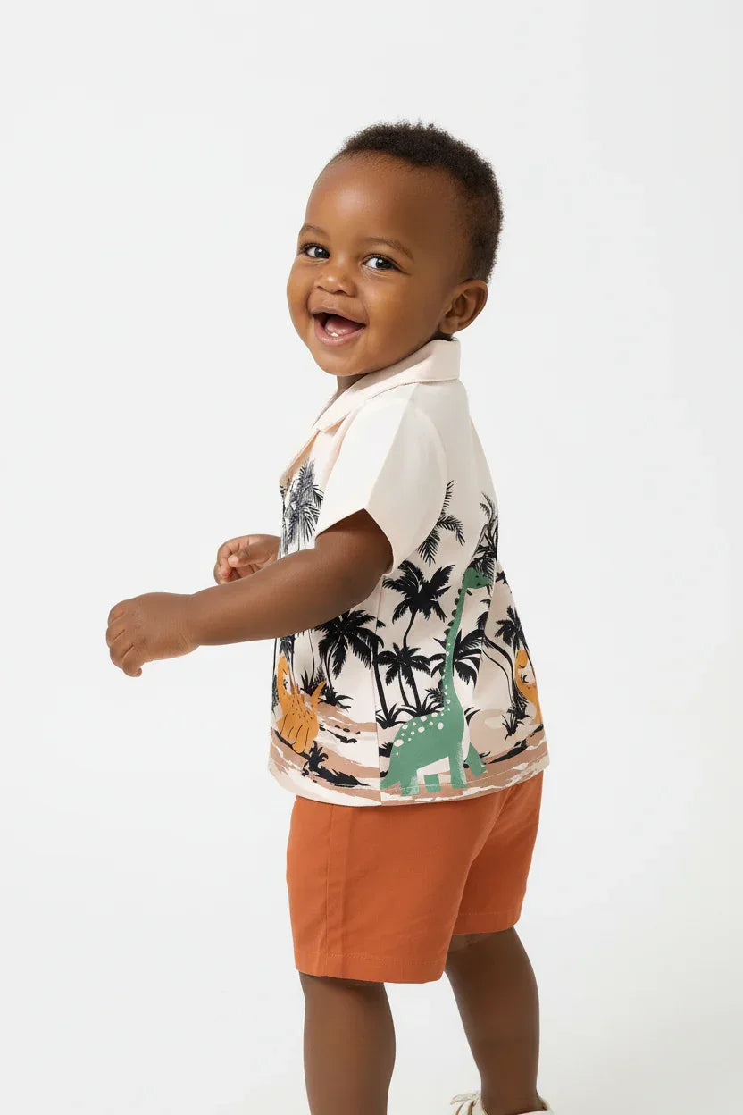 Vue de dos bébé garçon en ensemble dinosaures palmiers BabyCoton — chemise polo beige imprimée et short terracotta, fond blanc