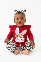  bébé riant ensemble BabyCoton — body lapin rouge, pantalon léopard nœud et bandeau, moment de joie fond blanc