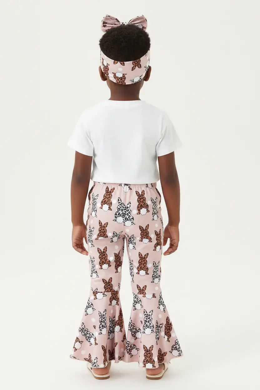Vue de dos fillette en ensemble Happy Easter BabyCoton — t-shirt blanc, pantalon évasé rose imprimé lapins léopard et bandeau nœud, fond blanc