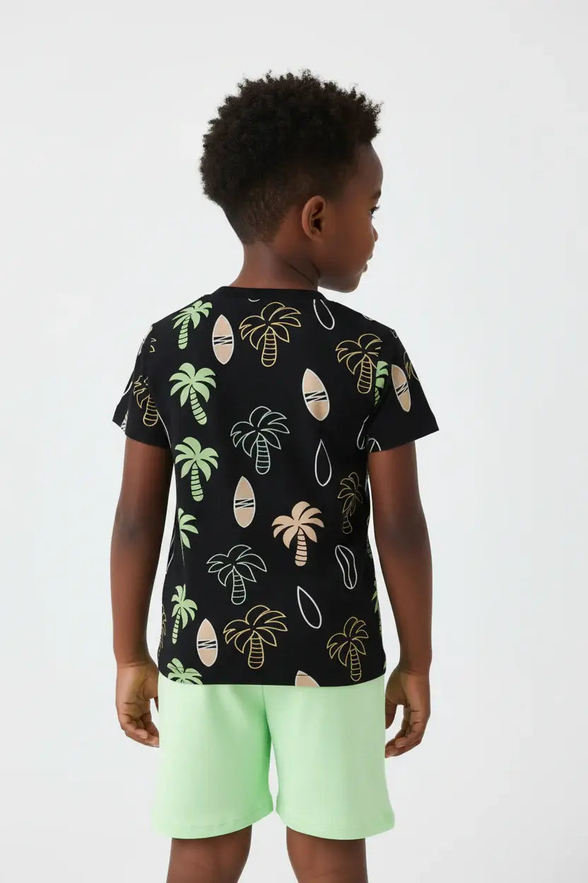 Vue de dos garçon en ensemble palmiers tropicaux BabyCoton — t-shirt noir all-over palmiers et short vert fluo, fond blanc