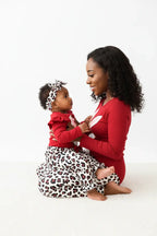 Maman et bébé fille de profil en ensemble rouge BabyCoton — body lapin rouge, pantalon léopard nœud et bandeau, regard complice fond blanc