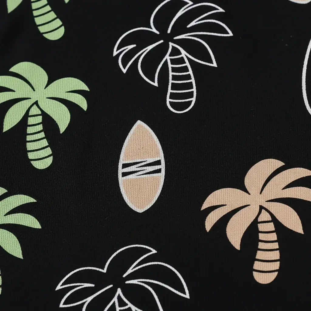 Détail gros plan imprimé palmiers tropicaux et planches de surf — t-shirt noir all-over garçon BabyCoton, vert beige blanc, fond blanc