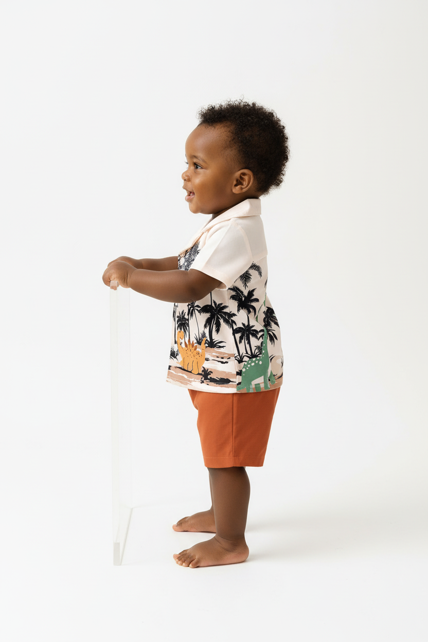 	Vue de profil bébé garçon en ensemble dinosaures palmiers BabyCoton — silhouette complète chemise polo beige et short terracotta, fond blanc
