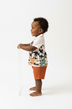 	Vue de profil bébé garçon en ensemble dinosaures palmiers BabyCoton — silhouette complète chemise polo beige et short terracotta, fond blanc