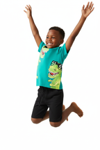 Garçon qui saute en ensemble dinosaures turquoise BabyCoton — t-shirt turquoise imprimé T-rex et short noir, mouvement dynamique fond blanc