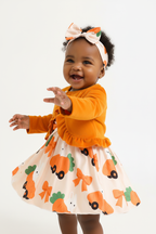 Bébé fille en mouvement 3/4 en ensemble orange BabyCoton — cardigan manches longues orange, robe carottes nœuds plissée et bandeau, fond blanc