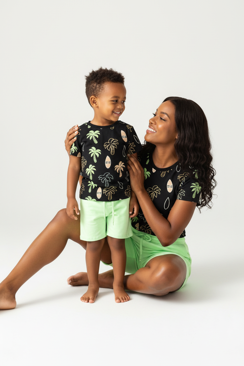 	Maman et garçon moment complice — ensemble palmiers tropicaux BabyCoton, t-shirt noir palmiers planches surf et short vert fluo, fond blanc