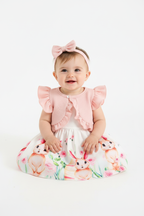Bébé fille en ensemble robe blanche lapins roses boléro rose volants bandeau nœud - pose assise adorable expression douce - BabyCoton