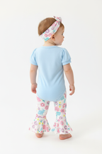Bébé fille en ensemble Pâques body bleu lapin et pantalon évasé lapins fleurs - vue de dos montrant pantalon évasé coloré et bandeau fleuri - BabyCoton