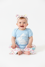 Bébé fille en ensemble Pâques body bleu Happy Easter pantalon évasé lapins fleurs - pose assise adorable expression douce - BabyCoton