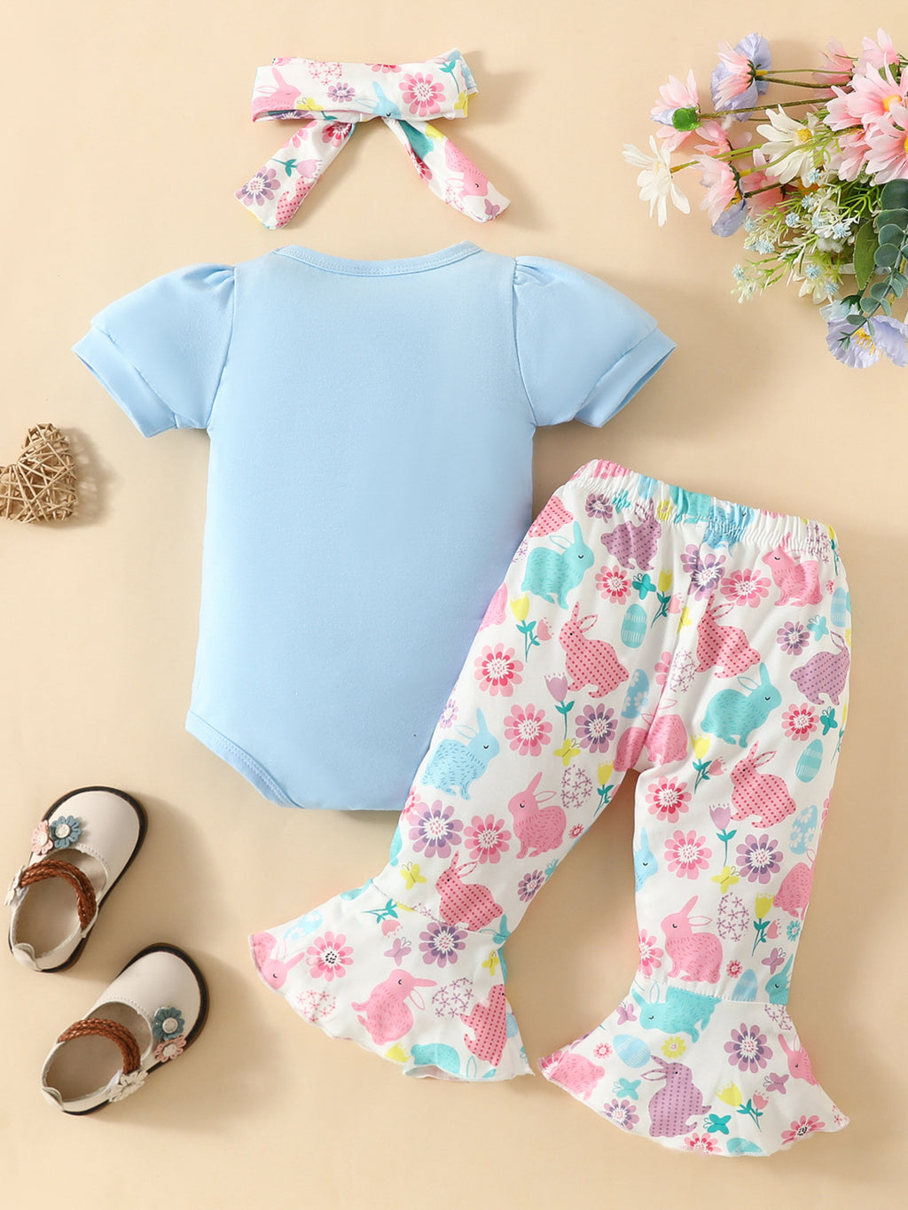 Body bleu ciel bébé fille Happy Easter - manches courtes bouffantes, grand lapin blanc silhouette avec texte Happy Easter cursif sur poitrine - ensemble avec pantalon évasé lapins fleurs multicolores et bandeau fleuri - BabyCoton
