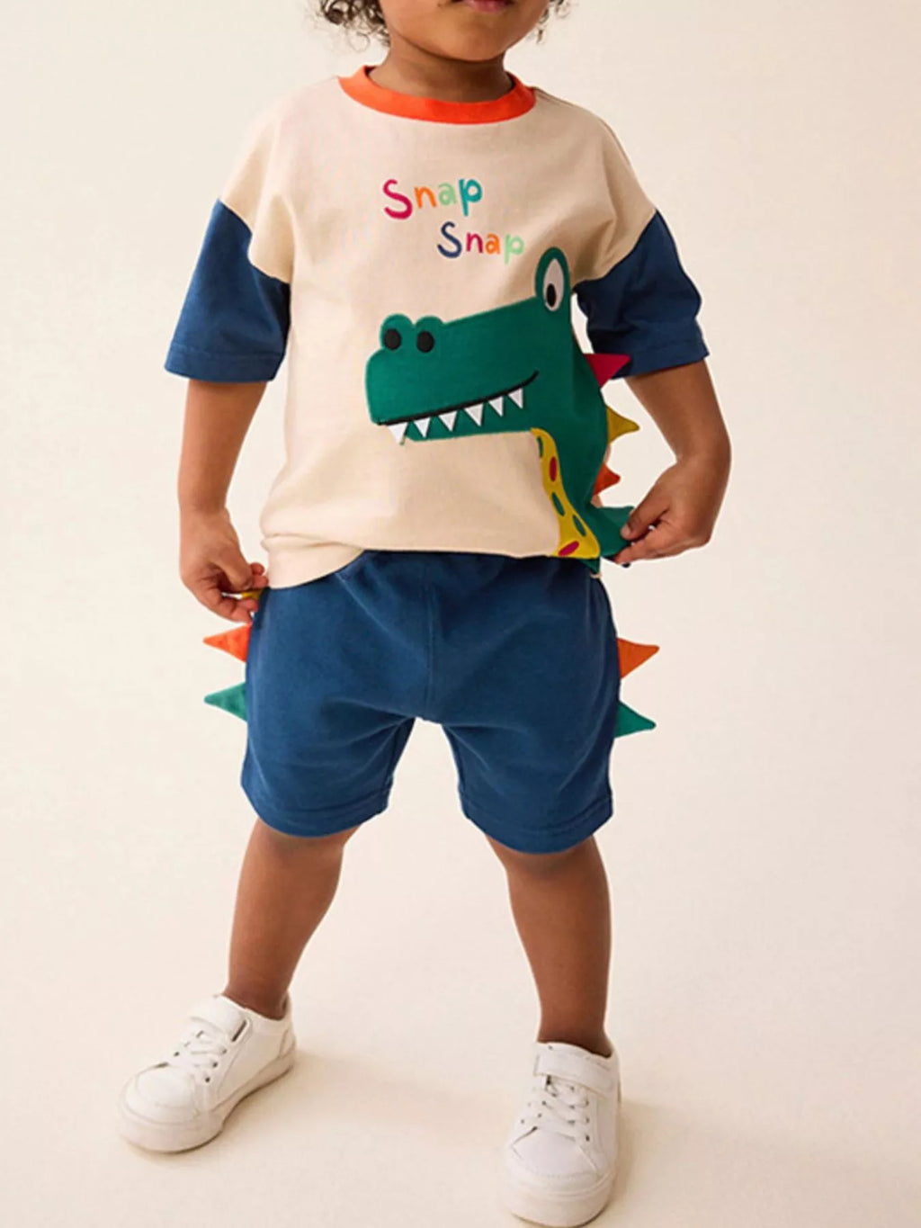 🦕 Enfant portant un ensemble 2 pièces avec appliqué dinosaure en relief - vue de face montrant le détail texturé et coloré qui captive les petits paléontologues