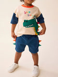 🦕 Enfant portant un ensemble 2 pièces avec appliqué dinosaure en relief - vue de face montrant le détail texturé et coloré qui captive les petits paléontologues