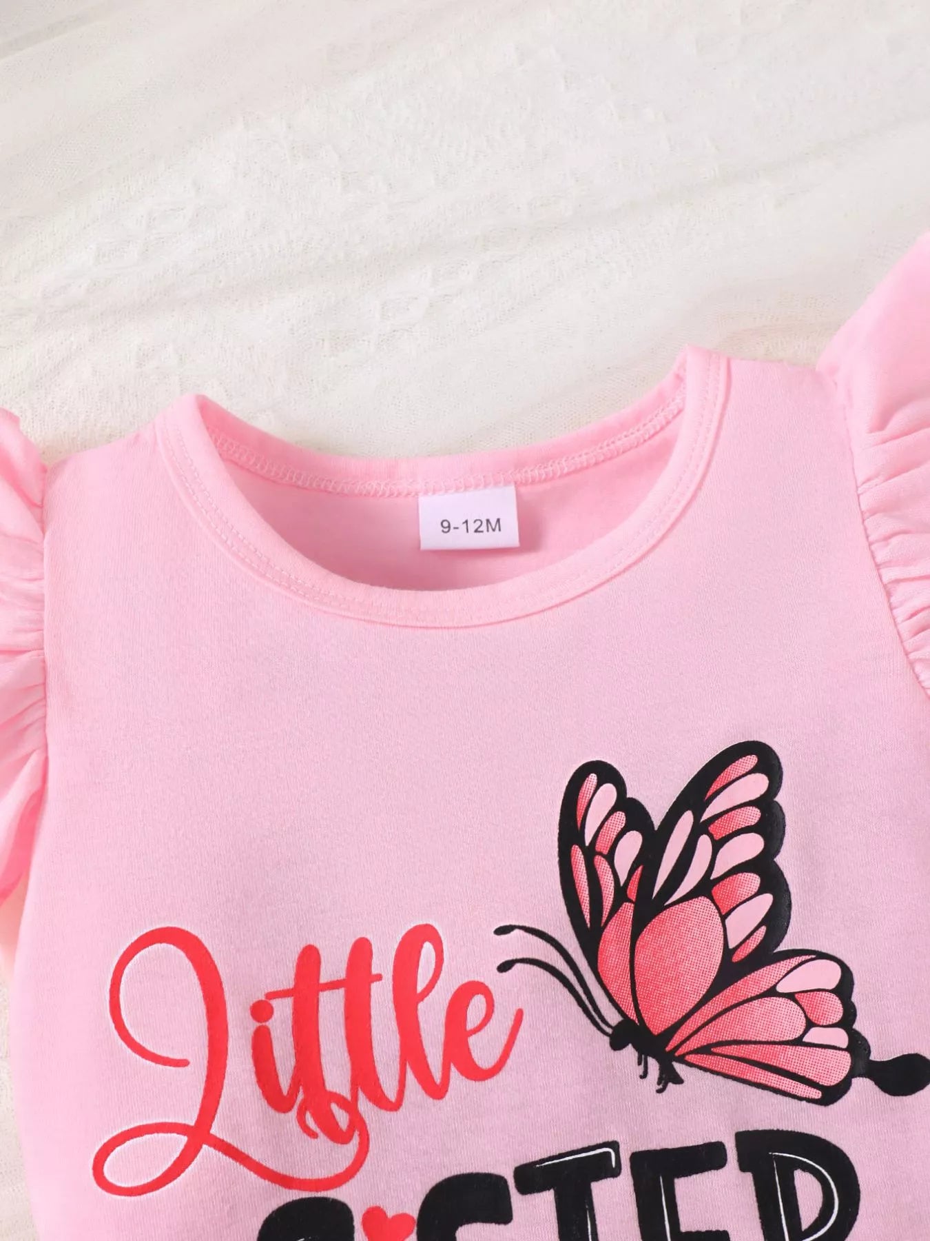 🦋 Détail rapproché des imprimés papillons colorés et du message 'Little Sister' - motifs enchanteurs et volants délicats qui apportent grâce et féminité