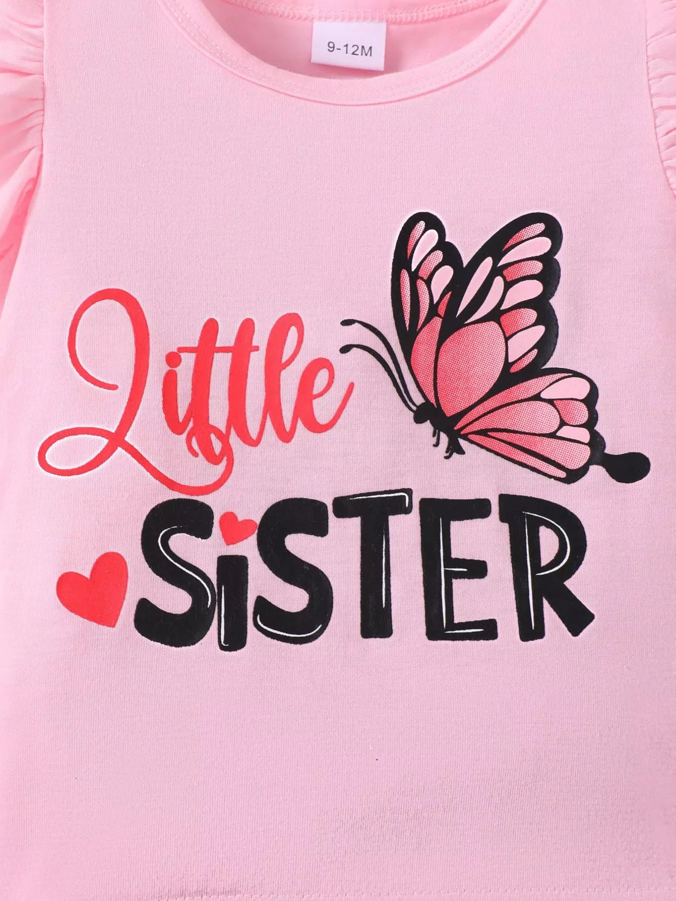 🌸 Gros plan sur les détails de qualité - volants soignés, imprimés papillons résistants et message 'Little Sister' fièrement affiché

