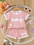 🍯 Enfant portant un ensemble t-shirt tricot gaufré imprimé miel et fleurs et short - vue de face montrant la texture unique et les motifs gourmands