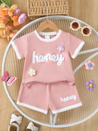 🍯 Enfant portant un ensemble t-shirt tricot gaufré imprimé miel et fleurs et short - vue de face montrant la texture unique et les motifs gourmands