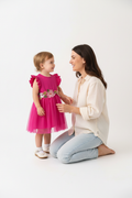 Maman agenouillée avec sa fille en robe tulle fuchsia manches volantées ceinture fleurs 3D brodées - moment tendresse mère et enfant - BabyCoton