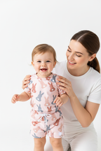 Maman debout derrière sa fille en ensemble lapins silhouettes rose gris - mains sur les épaules sourires complices mère et enfant - BabyCoton