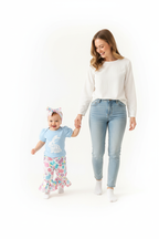 Maman tenant la main de sa fille en ensemble Pâques body bleu lapin Happy Easter pantalon évasé lapins fleurs - promenade joyeuse ambiance printanière - BabyCoton