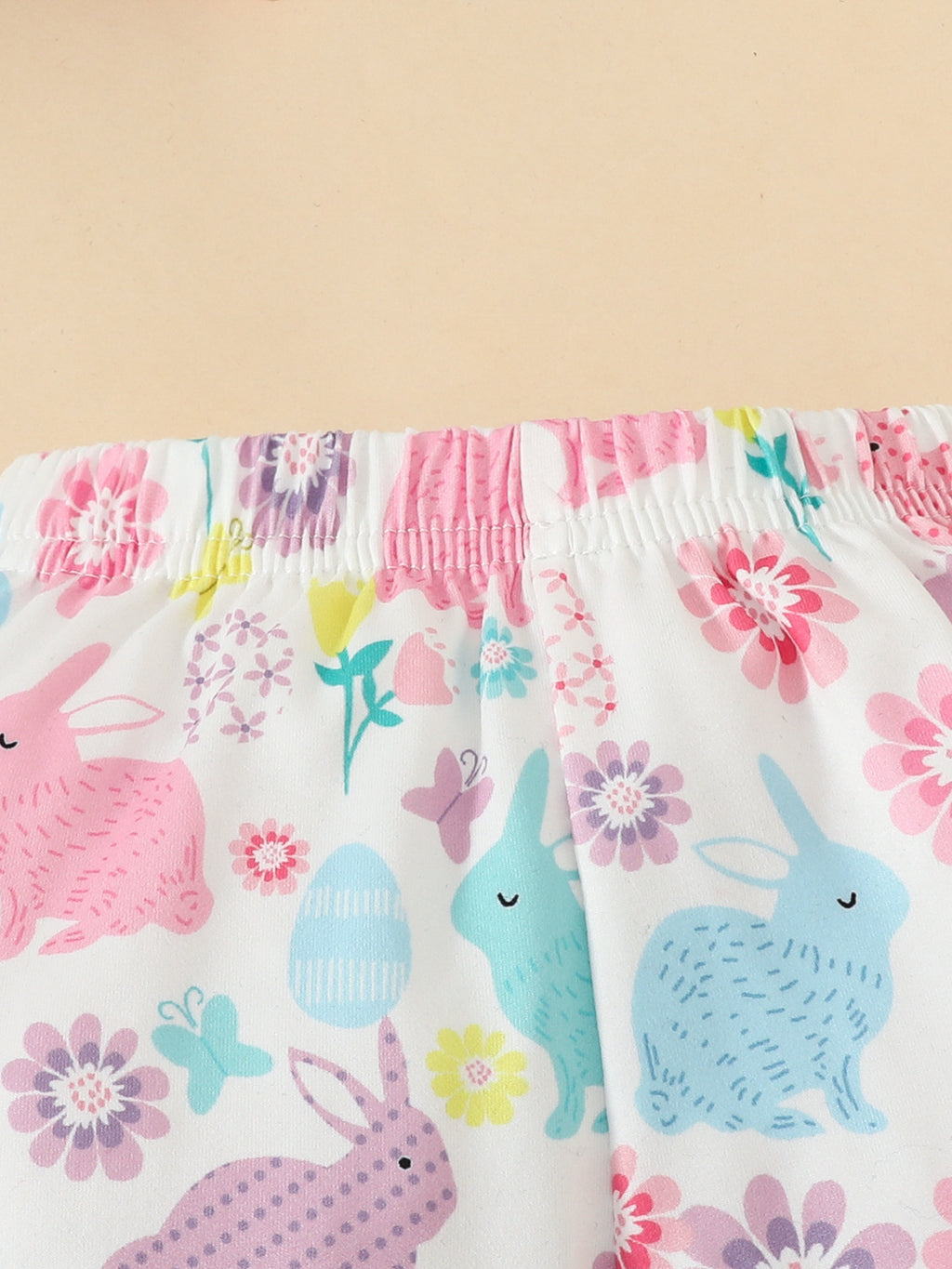 Pantalon évasé bébé fille lapins Pâques - blanc imprimé lapins colorés roses turquoise violets et fleurs printanières multicolores, taille élastique confortable - assorti body bleu ciel Happy Easter et bandeau fleuri - BabyCoton
