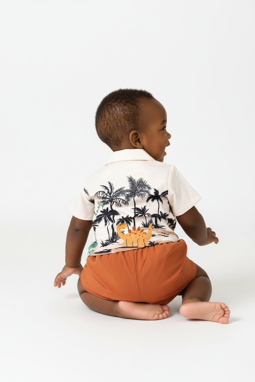 Vue 3/4 dos bébé garçon se retournant en ensemble dinosaures palmiers BabyCoton — chemise polo beige dinos palmiers et short terracotta, fond blanc