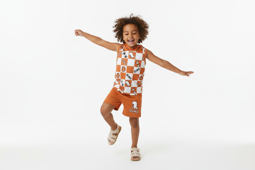 Enfant dansant avec bonheur en portant un débardeur à capuche orange à carreaux avec motifs dinosaures DINO et short orange assorti
