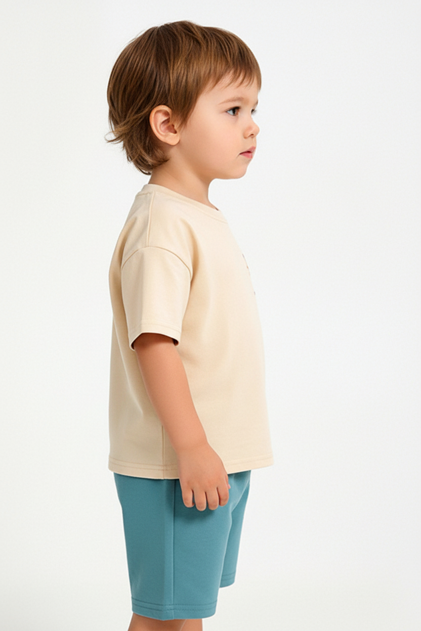 Enfant en ensemble dinosaure beige et bleu - t-shirt manches courtes dinosaure et short bleu turquoise - vue de côté - BabyCoton