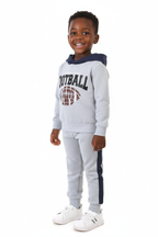 Enfant portant ensemble hoodie football graphique et pantalon - vue trois-quarts - détail design sportif énergique - photo produit fond blanc - BabyCoton Suisse
