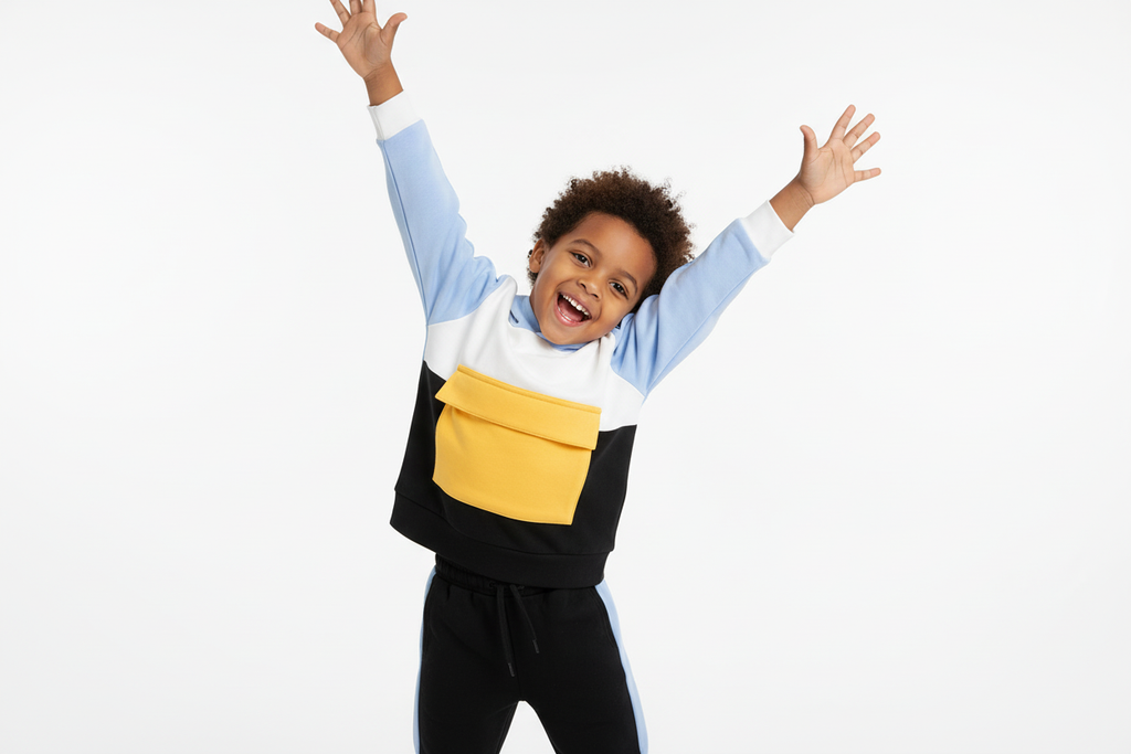 Enfant  jouant activement en portant un hoodie color block blanc, bleu ciel, jaune et noir avec pantalon noir à bandes bleues
