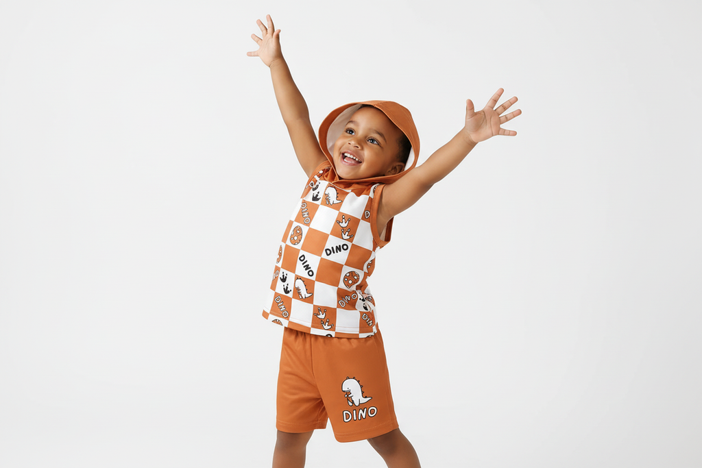 Enfant jouant activement en portant un débardeur à capuche orange à carreaux avec motifs dinosaures DINO et short orange assorti
