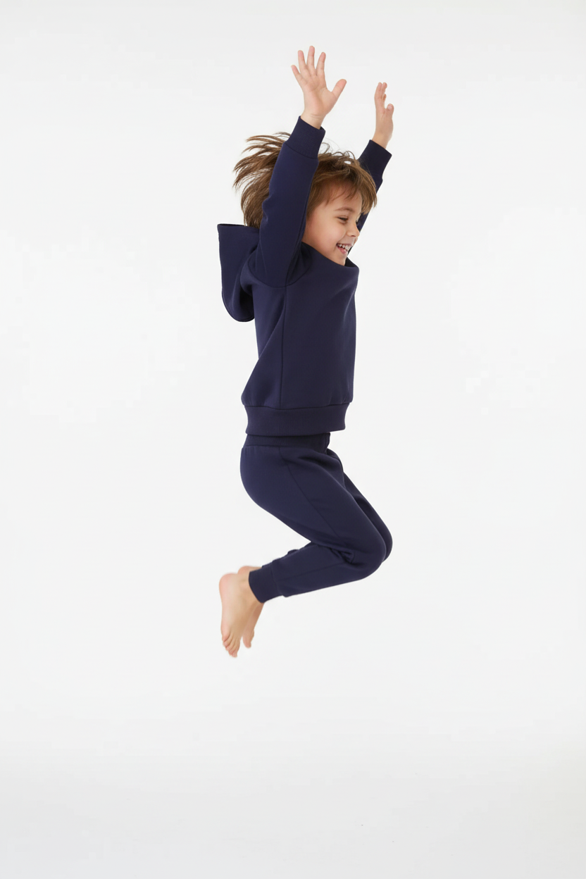 Enfant sautant avec ensemble bleu marine - vue de profil « Enfant tournoyant en ensemble bleu marine à capuche - vue trois-quarts arrière »