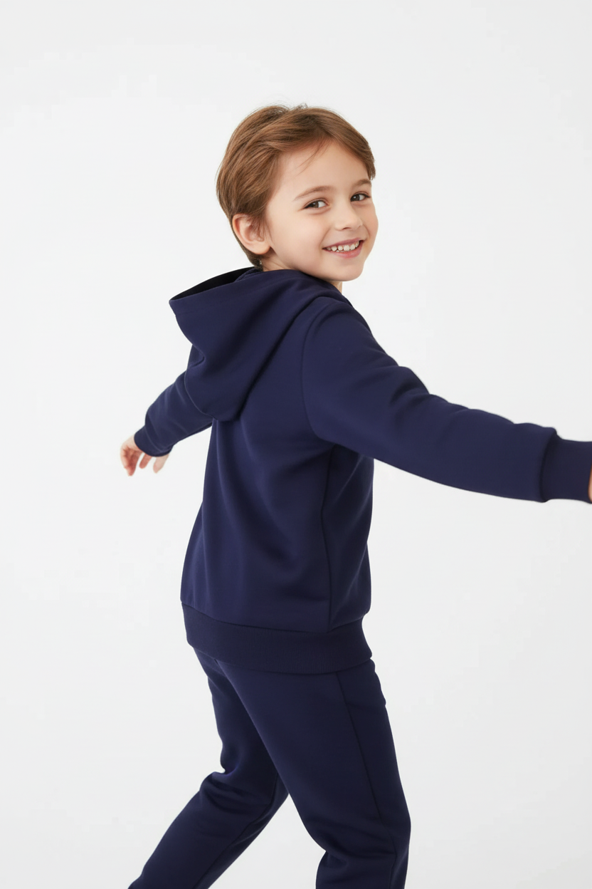 Enfant tournoyant avec ensemble bleu marine - vue arrière « Enfant accroupi en pose énergique portant sweat à capuche et pantalon bleu marine »
