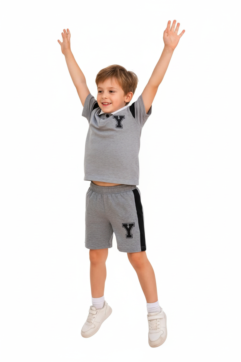 "Enfant 6 ans sautant de joie bras levés vers le haut - Ensemble polo et short gris chiné sportif - Polo col blanc avec bordures noires, logo Y noir appliqué sur poitrine, manches courtes avec détails noirs - Short coordonné gris avec bandes latérales noires contrastantes et logo Y - Vue trois-quarts angle diagonal montrant mouvement dynamique - Tenue athlétique confortable - Fond blanc studio professionnel - Photo produit lifestyle action BabyCoton Suisse - Style sportif décontracté garçon 3-8 ans"