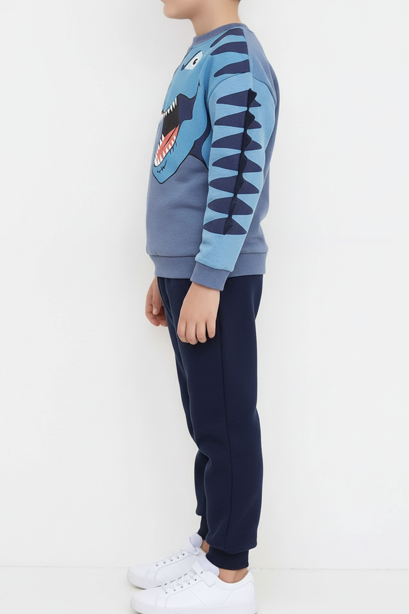 "Ensemble 2 pièces dinosaure enfant - Vue latérale de côté montrant sweat bleu gris avec pointes dinosaure 3D sur manche et pantalon jogging bleu marine - Silhouette complète de l'ensemble - Coupe sportive confortable visible - Fond blanc professionnel - Photo produit e-commerce BabyCoton"