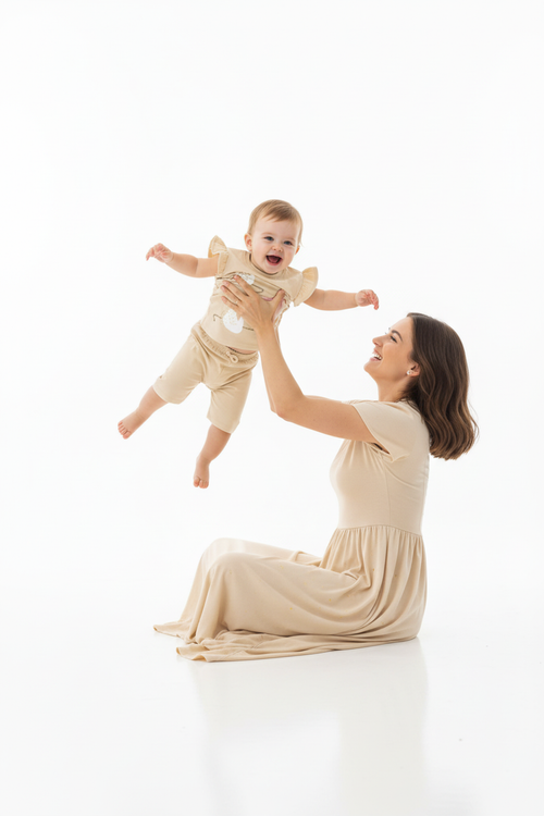 Maman qui soulève bébé vers le ciel, bébé les bras écartés, vue du bas.
