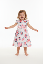 Fille en robe blanche plissée fleurie roses roses rouges feuilles bleues - col volant ceinture satin rose jupe plissée évasée - vue de face - BabyCoton