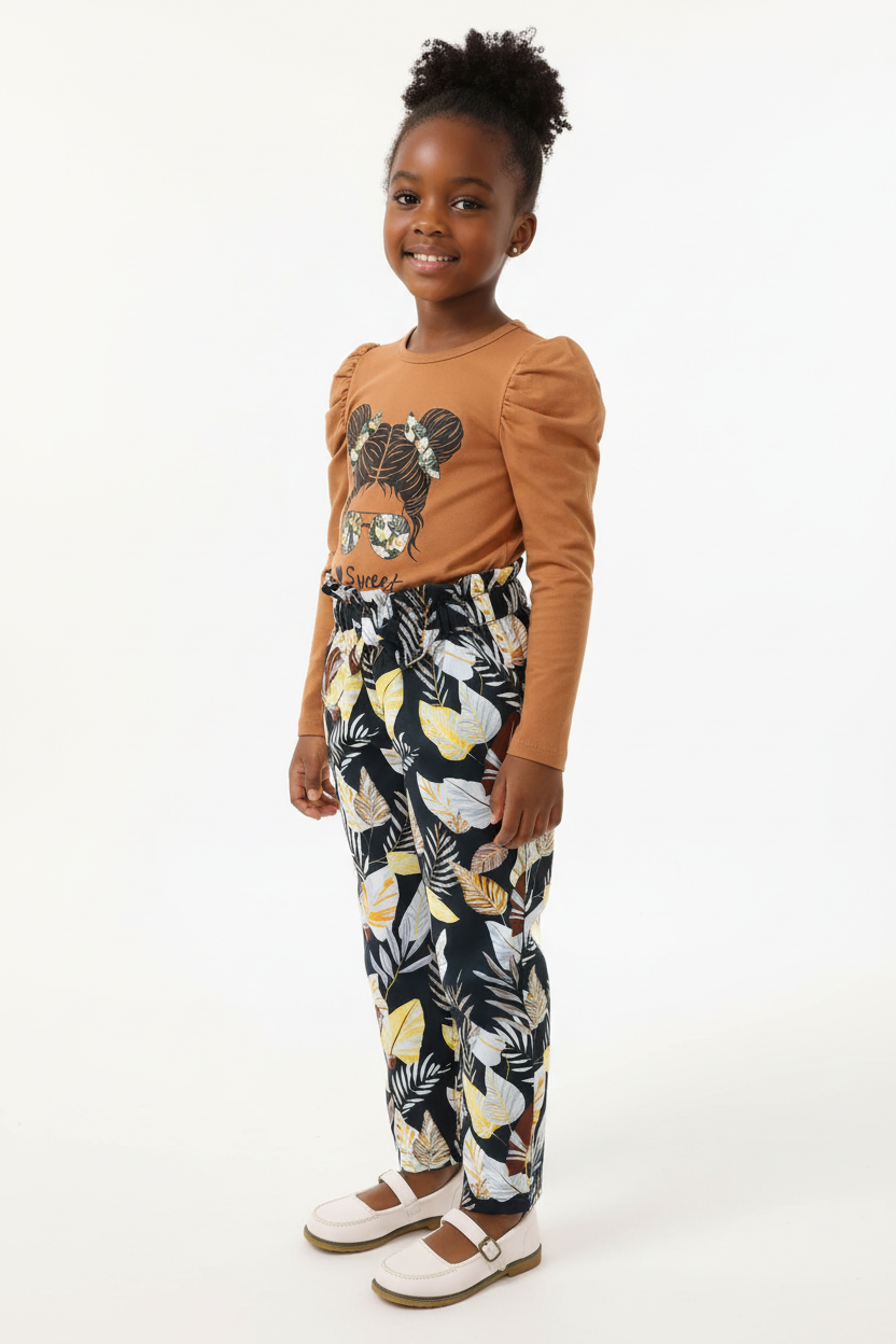 Fillette portant ensemble haut graphique et pantalon floral - vue trois-quarts - détail design bohème élégant - photo produit fond blanc - BabyCoton Suisse
