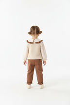 Fillette portant ensemble haut avec appliqués floraux et volants avec pantalon coordonné - vue de dos montrant arrière du haut fleuri - finitions soignées - fond blanc studio professionnel - BabyCoton
