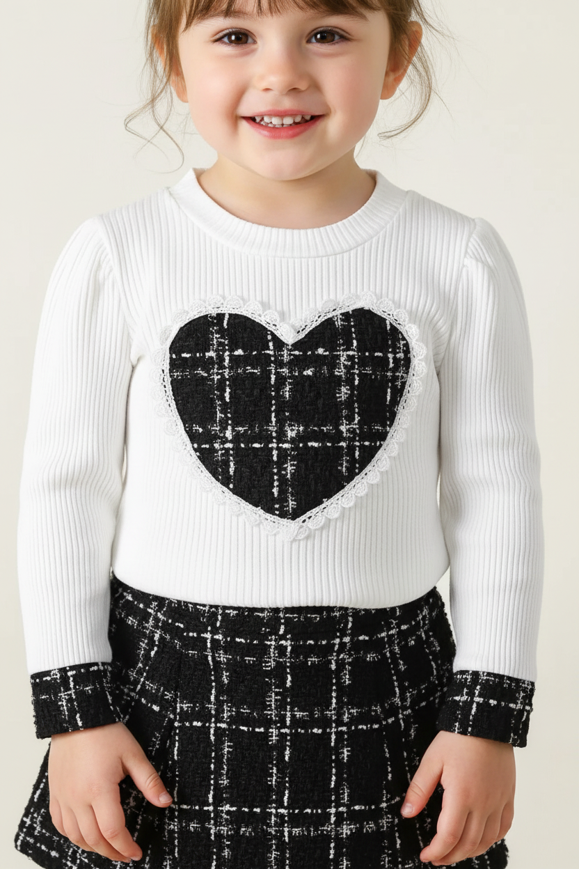 Gros plan détail ensemble haut avec motif cœur romantique sur fond carreaux champêtres - motif cœur et carreaux visibles - fillette souriante heureuse - finitions premium - BabyCoton
