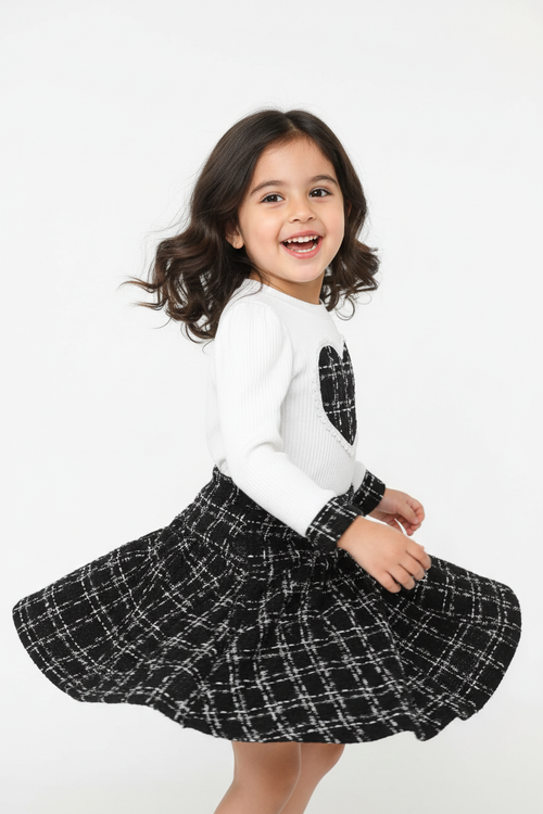 Fillette tournoyant dans ensemble haut cœur à carreaux et jupe - pose dynamique jupe en mouvement - enfant heureuse joyeuse - style romantique champêtre élégant - fond blanc studio professionnel - BabyCoton Suisse
