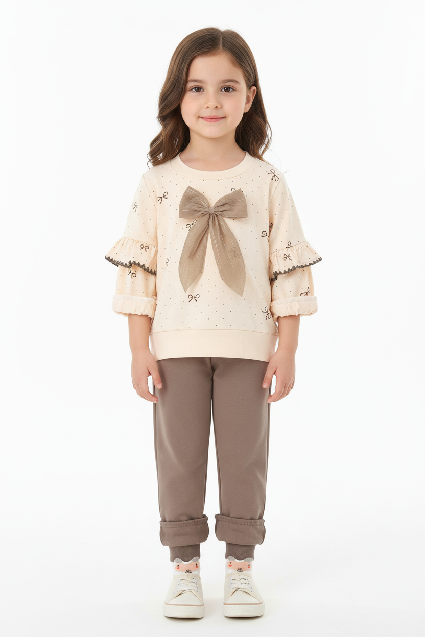 Fillette portant ensemble 2 pièces haut avec nœud adorable et manches à volants romantiques avec pantalon coordonné - vue de face complète - style romantique chic élégant - fond blanc studio professionnel - vêtements fille BabyCoton Suisse
