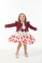 Fillette tournoyant dans ensemble robe nœud et cardigan à volants - pose dynamique robe et cardigan en mouvement - enfant heureuse joyeuse - style élégant princier romantique - fond blanc studio professionnel - BabyCoton Suisse
