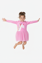Fillette sautant en l'air avec joie en portant la robe tulle licorne rose manches longues - fond blanc studio