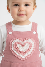 Gros plan bébé avec cœur 3D rose et blanc sur salopette