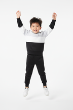 Enfant en pose ludique avec ensemble hoodie casual bicolore - photographie studio professionnelle fond blanc