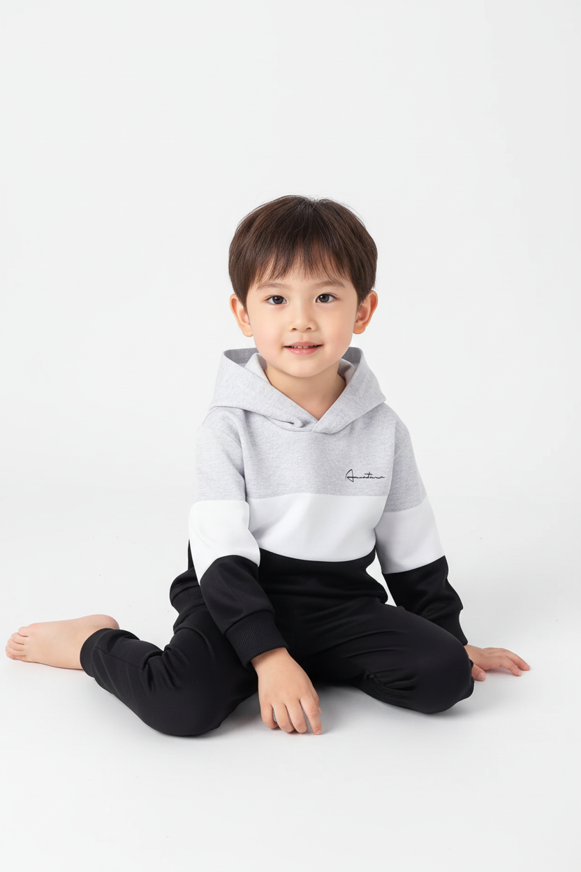 Enfant assis portant ensemble hoodie color block blanc noir et pantalon - vue complète confortable