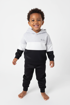 Enfant souriant face caméra avec ensemble hoodie casual blanc et noir - portrait studio chaleureux