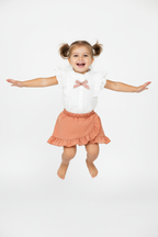 Petite fille en ensemble blanc et rose corail - saut joyeux